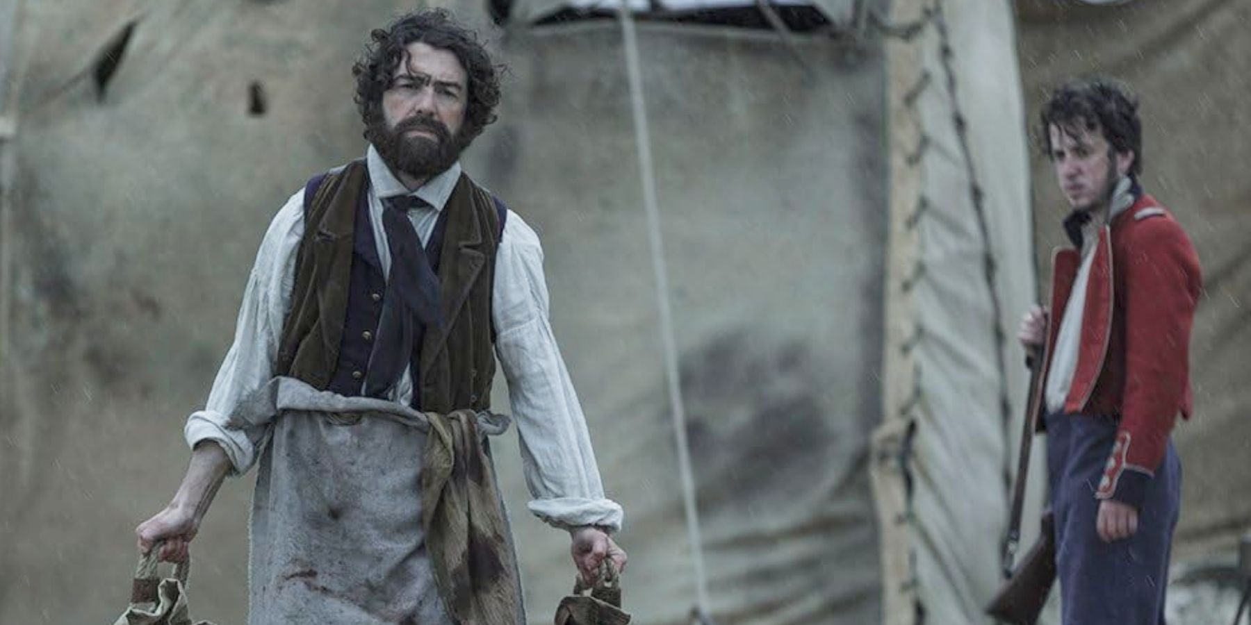 Le Dr Henry Goodsir (Paul Ready) transportant des sacs d'un camp de soldats dans The Terror