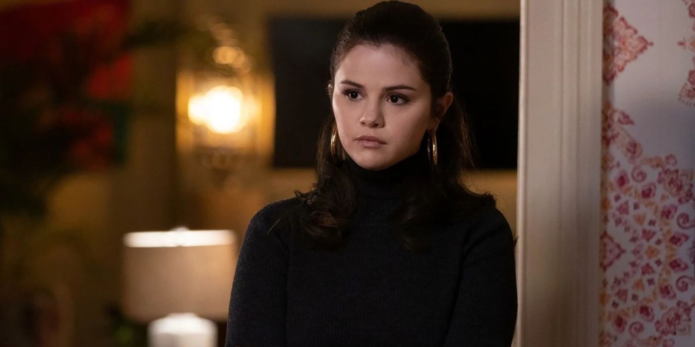 Mabel debout devant une porte portant un col roulé noir dans Only Murders in the Building.