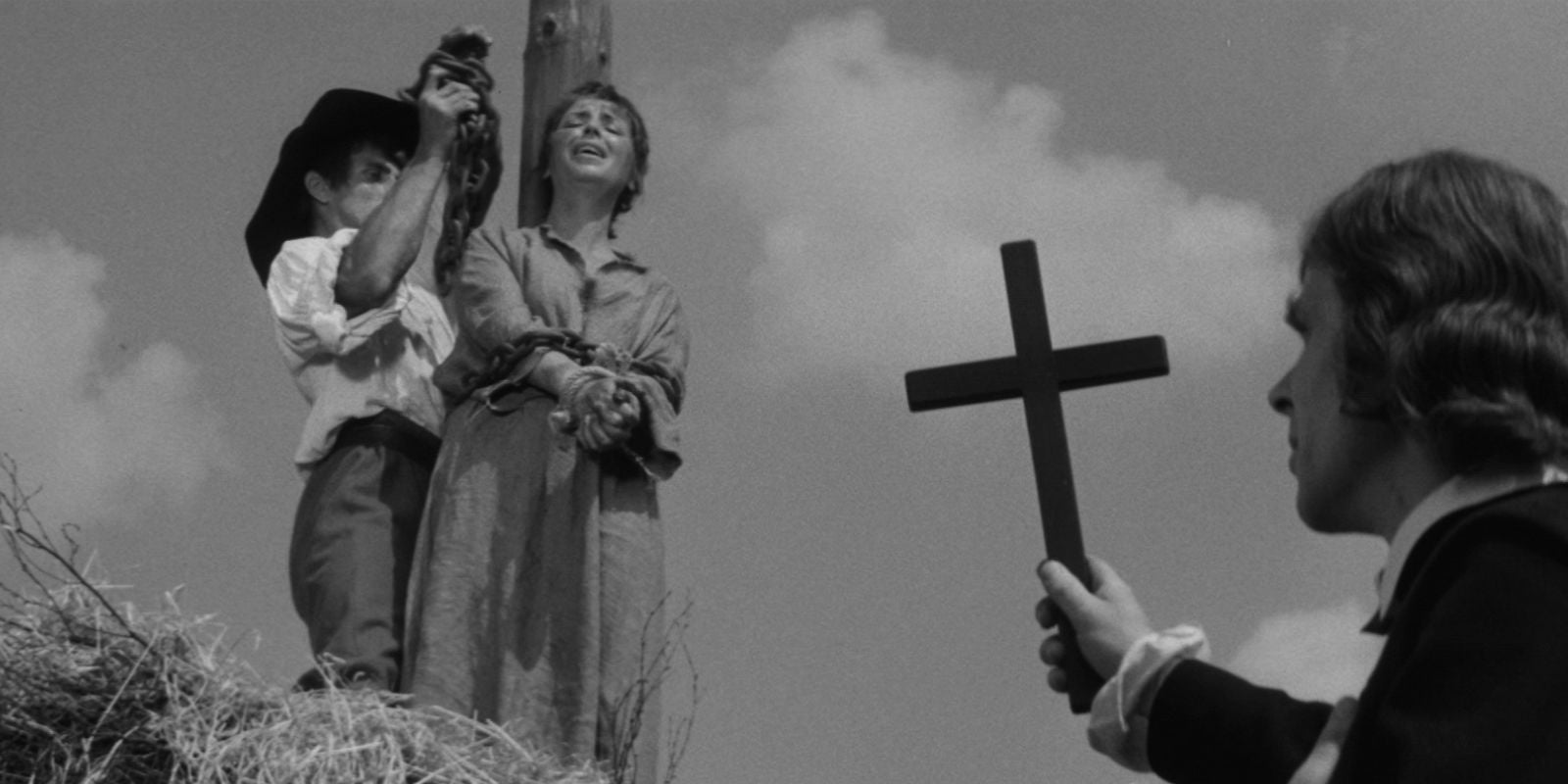 Un prêtre pointe une croix vers une femme hurlante sur le bûcher dans Witchhammer 1970